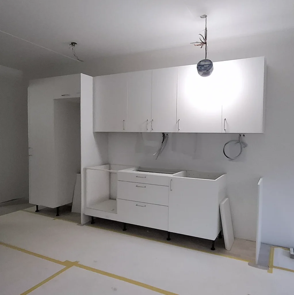 Montering av vitt kök med väggskåp och bänkskåp under renovering i Bjurbäcken