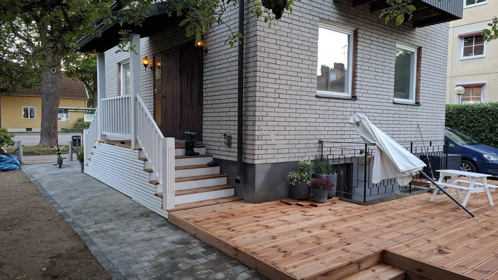 Nybyggd träterrass med trappa och vitt räcke vid villa i Stockholm